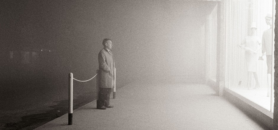 Mann steht Nachts vor einem Schaufenster und betrachtet die Auslage. Schwarz-Weiß-Foto