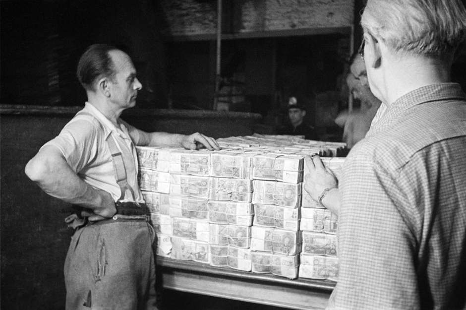 Zwei Männer stehen neben einem Tisch mit gebündelten Geldscheinen