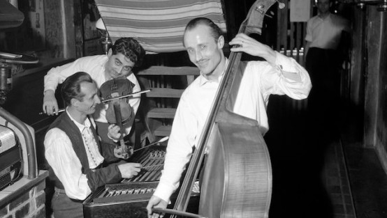 Drei Jazz-Musiker mit Kontrabass, Geige und Zither spielen in einem Kellerlokal