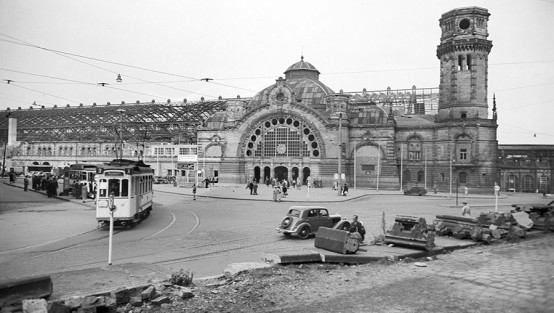 Schwarz-Weiss-Aufnahme einer historische Straßenbahn vor dem noch kriegsbeschädigten Kölner Hauptbahnhof im Jahr 1949