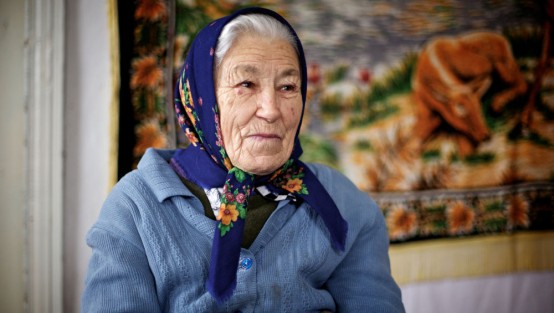 Alte Frau mit Kopftuch und blauer Strickjacke