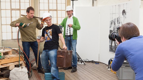 Fotografin bei der Gruppenaufnahme von drei Männern mit Werkzeug